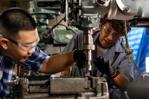 Asian worker in production plant drilling at machine. Professional worker near drilling machine on factory. finishing metal working internal steel surface on lathe grinder machine with flying sparks. photo