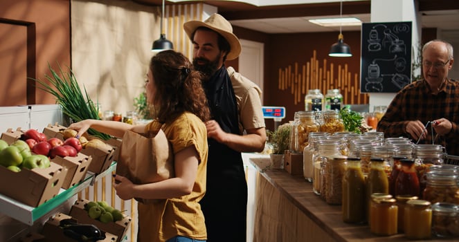 Vendor helping client choose products in chemicals free food supermarket, inviting her to checkout counter. Customer in local store using renewable energy ready to buy pantry staples photo