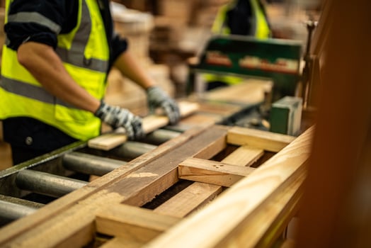 A worker cleans timber pieces in a warehouse, preparing them for further processing. photo