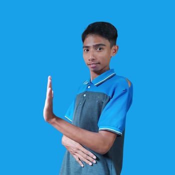 young Asian man with stop hand. with a serious face wearing a blue t-shirt, isolated on a blue background photo