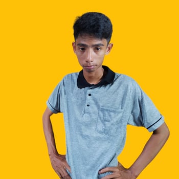 an Asian man holding his waist wearing a gray t-shirt. isolated yellow background. photo