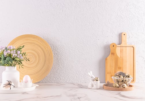 Festive decorations of kitchen stone countertop for Easter day. wooden kitchen utensils, ceramic bunny , vase of flowers. Eco-friendly kitchen. photo