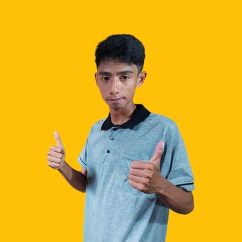 young asian man gesturing okay wearing gray t-shirt, isolated yellow background. photo