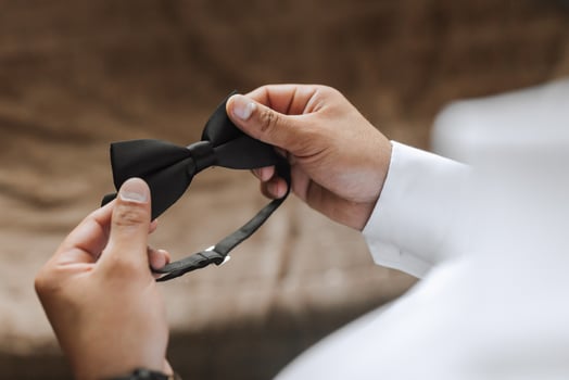 Young groom wearing bow tie, hands close-up, looking at camera. The man is wearing a shirt. The groom is preparing for the wedding. photo