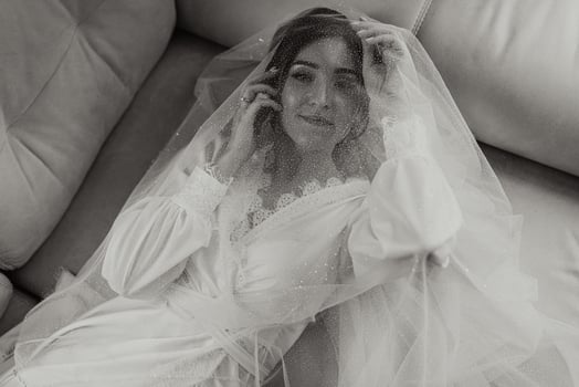 a beautiful bride is lying on a modern sofa in a white robe. Wedding hairstyle, professional make-up. Romantic bride posing photo