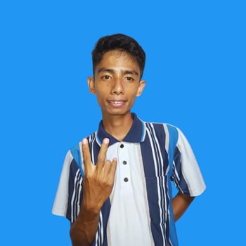 Outward looking young Asian man wearing colorful t-shirt, copy space index finger with new idea, isolated on blue background photo