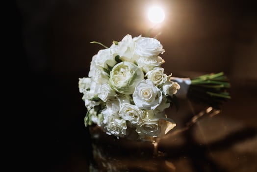 Accessories on the groom's wedding day. A bouquet of white roses on a dark background with backlight. Men's fashion photo