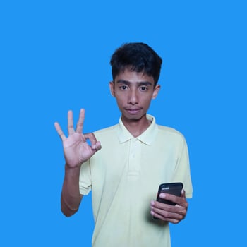 Asian man smiling face with okay gesture, isolated on blue background photo