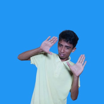 young asian man hands stop. with a serious face wearing a yellow t-shirt, isolated on a blue background photo
