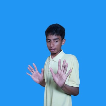 young asian man hands stop. with a serious face wearing a yellow t-shirt, isolated on a blue background photo