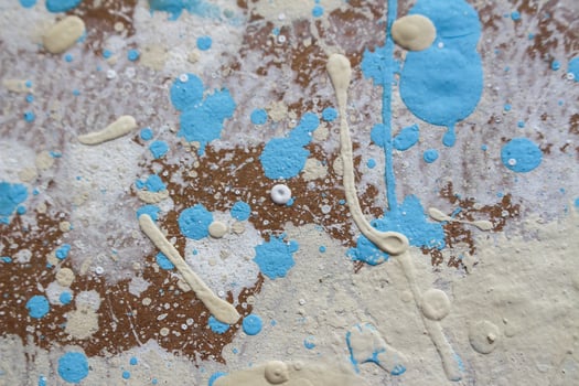 Abstract spots, drops of yellow blue white paint on a brown wooden surface photo