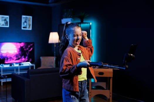 Child joins viral dance craze inspired by beloved celebrities, recording family friendly video with cellphone attached to selfie stick. Cute girl does latest internet dancing challenge photo