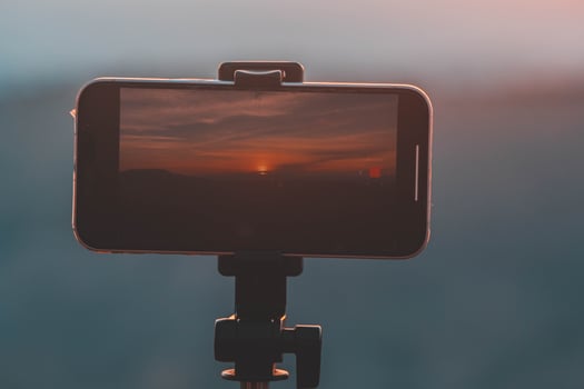 A smartphone is recording the sun setting over a mountain range. photo