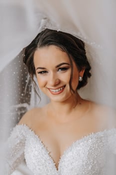 Wedding portrait. The bride in an elegant wedding dress poses wrapped in a veil. Morning of the bride. Beautiful hair and makeup photo
