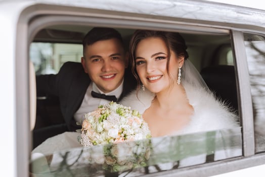 Beautiful bride and groom looking at the camera while sitting in a stylish white car. Beautiful wedding. Smiling wedding couple photo