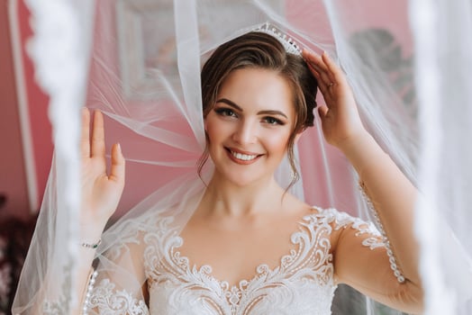 Beautiful bride, attractive woman in a wedding dress, under a veil, fashionable hairstyle and makeup. Happy bride woman. Smiling bride. Wedding day. A gorgeous bride. Marriage. photo