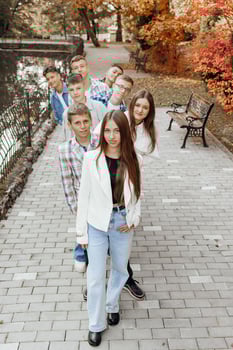 friendship, movement, action, freedom and people concept - group of happy teenagers or school friends posing and having fun outdoors against nature or forest background. photo