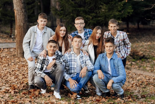 friendship, movement, action, freedom and people concept - group of happy teenagers or school friends posing and having fun outdoors against nature or forest background. photo