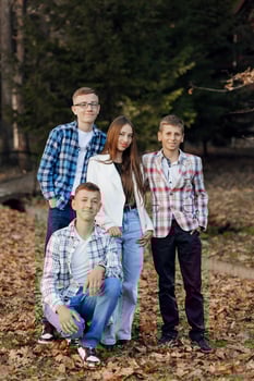 Four teenagers of different sexes, posing in nature. Teenage classmates are resting against the background of an autumn forest. photo