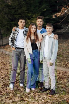 Four teenagers of different sexes, posing in nature. Teenage classmates are resting against the background of an autumn forest. photo