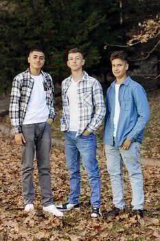 Three teenage boys, posing in nature, happy and having fun. Teenage classmates are resting against the background of an autumn forest. photo