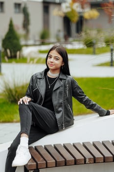 Vertical photo. Beautiful carefree young teenage girl in casual clothes. Portrait of a beautiful girl against the background of nature with a blurred background. photo