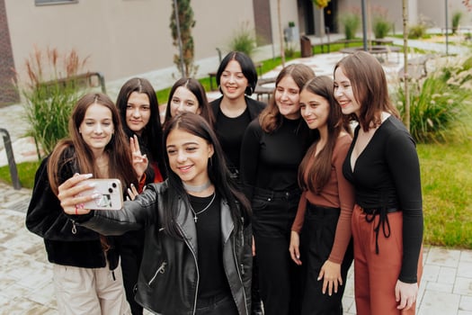 Friends taking a big group selfie smiling at the camera - laughing young people standing outdoors and having fun - portrait of cheerful schoolchildren outside school - human resources concept photo