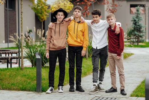 Group of smiling and happy teenage friends wearing casual clothes spending time together, posing and talking with each other near college building on autumn day. photo