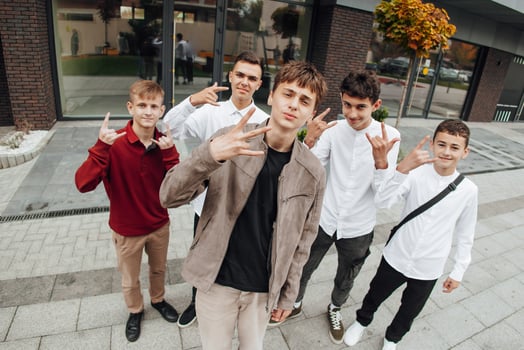 Group of smiling and happy teenage friends wearing casual clothes spending time together, posing and talking with each other near college building on autumn day. photo