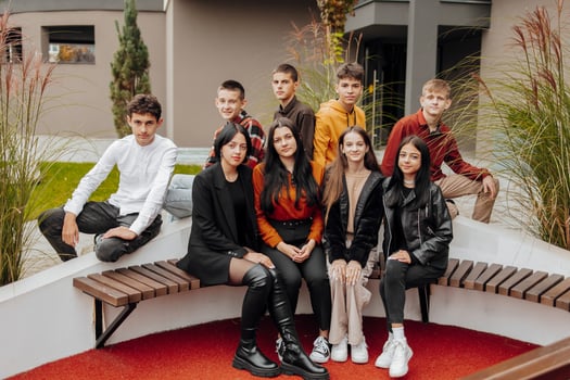 Group of smiling and happy teenage friends wearing casual clothes spending time together, posing and talking with each other near college building on autumn day. photo