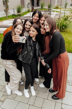 Friends taking a big group selfie smiling at the camera - laughing young people standing outdoors and having fun - portrait of cheerful schoolchildren outside school - human resources concept photo