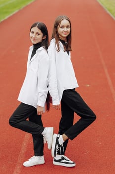 Portrait of two teenage girls in casual clothes sitting in a stadium and posing looking at the camera. Concept of friendship. A moment of happiness. photo
