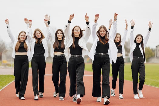 A group of many happy teenage girls dressed in the same outfit having fun and posing in a stadium near a college. Concept of friendship, moments of happiness. School friendship photo