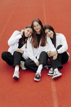 Portrait of three teenage girls in casual clothes sitting in a stadium and posing looking at the camera. Concept of friendship. A moment of happiness. photo