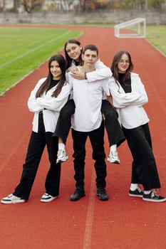 Portrait of four teenage in casual clothes sitting in a stadium and posing looking at the camera. Concept of friendship. A moment of happiness. photo