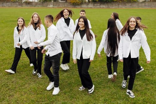 A group of many happy teenagers dressed in the same outfit having fun and posing in a stadium near a college. Concept of friendship, moments of happiness. School friendship photo