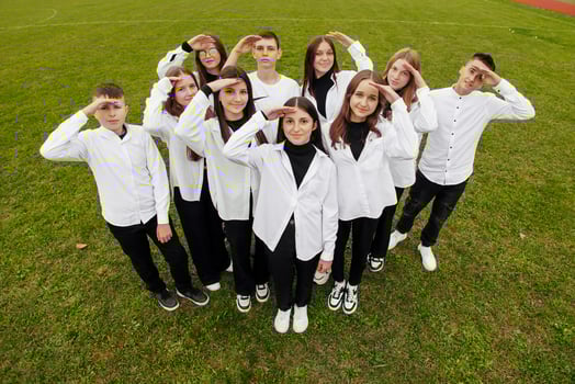A group of many happy teenagers dressed in the same outfit having fun and posing in a stadium near a college. Concept of friendship, moments of happiness. School friendship photo