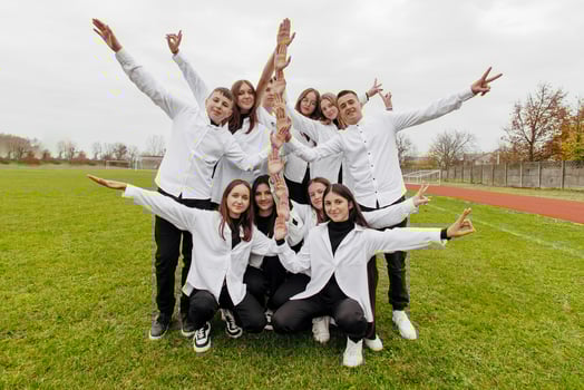 A group of many happy teenagers dressed in the same outfit having fun and posing in a stadium near a college. Concept of friendship, moments of happiness. School friendship photo