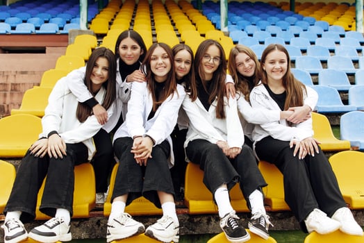 A group of many happy teenagers dressed in the same outfit having fun and posing in a stadium near a college. Concept of friendship, moments of happiness. School friendship photo