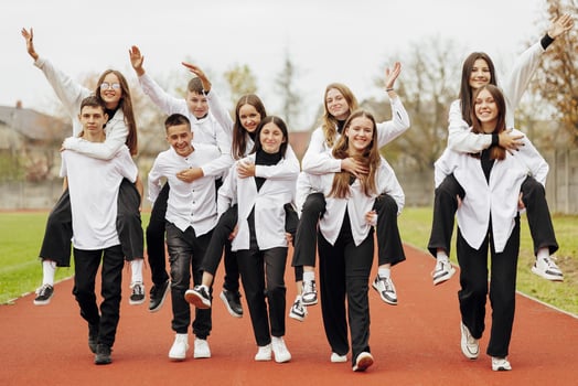 A group of many happy teenagers dressed in the same outfit having fun and posing in a stadium near a college. Concept of friendship, moments of happiness. School friendship photo