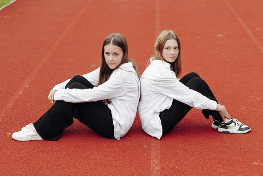 Portrait of two teenage girls in casual clothes sitting in a stadium and posing looking at the camera. Concept of friendship. A moment of happiness. photo