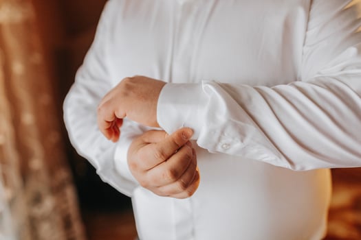 handsome business man buttoning shirt sleeves at home. The groom is preparing for the wedding. Close-up photo. photo
