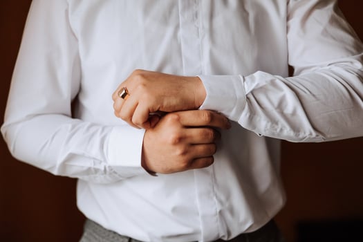 handsome business man buttoning shirt sleeves at home. The groom is preparing for the wedding. Close-up photo. photo