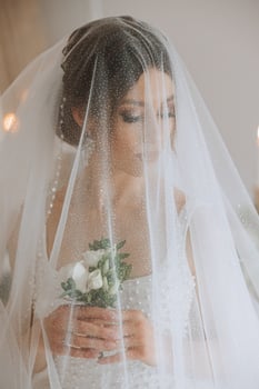 A luxurious bride with a beautiful hairstyle and a gorgeous dress is getting ready for the wedding ceremony in the morning. Morning photo of the bride at home or in a hotel room. Professional makeup.