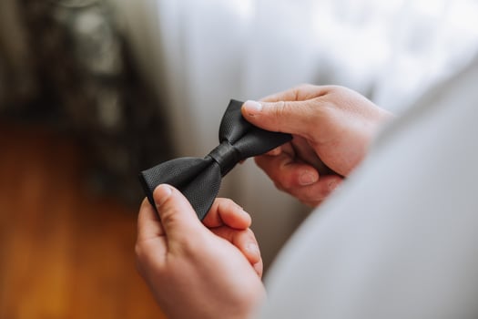 man's tie in hands, close-up photo of hands. The groom is preparing for the ceremony. Last preparations.