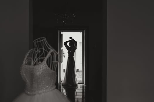 A happy bride is preparing for her luxurious wedding in a hotel room, with a wedding dress on a mannequin nearby. Portrait of a woman with fashionable hair, makeup and a smile in a dressing gown. photo