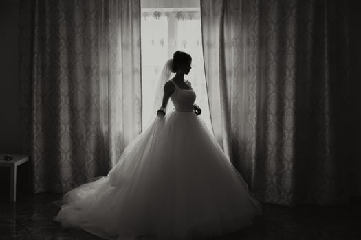 A luxurious bride with a beautiful hairstyle and a gorgeous dress is getting ready for the wedding ceremony in the morning. Morning photo of the bride at home or in a hotel room. Professional makeup.