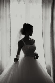 fashion photo of a beautiful bride with dark hair in an elegant wedding dress and stunning makeup in the room on the morning of the wedding. The bride is preparing for the wedding