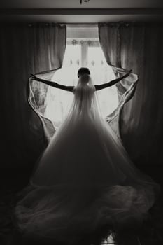 A luxurious bride with a beautiful hairstyle and a gorgeous dress is getting ready for the wedding ceremony in the morning. Morning photo of the bride at home or in a hotel room. Professional makeup.