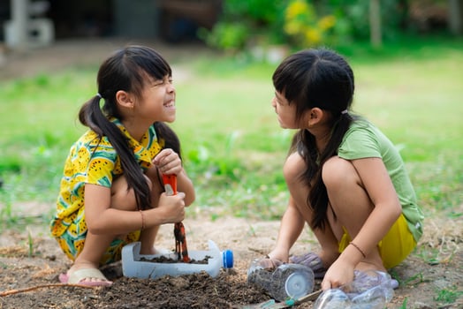 Little girl planting plants in pots from recycled water bottles in the backyard. Recycle water bottle pot, gardening activities for children. Recycling of plastic waste photo